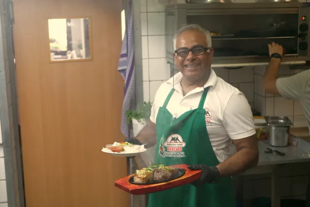 Gastgeber des Parejas mit einem Steak auf der Gusseisenplatte