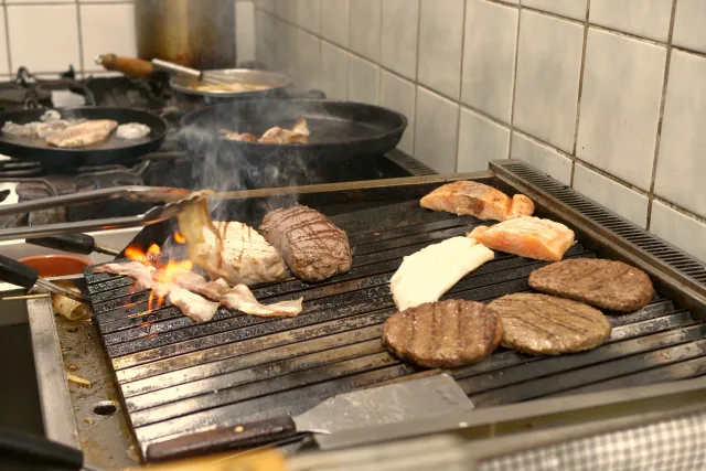 Steaks und Burger auf dem Grill über offener Flamme