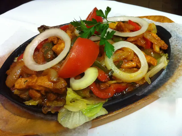 Fajita-Pfanne mit Zwiebelringen, Tomate und Salat
