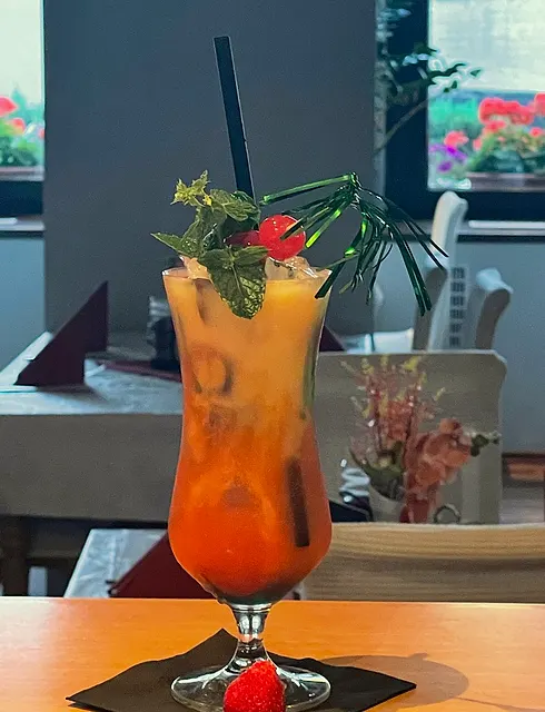 Ein Cocktail mit Minze und Erdbeere, im Hintergrund der Gastraum